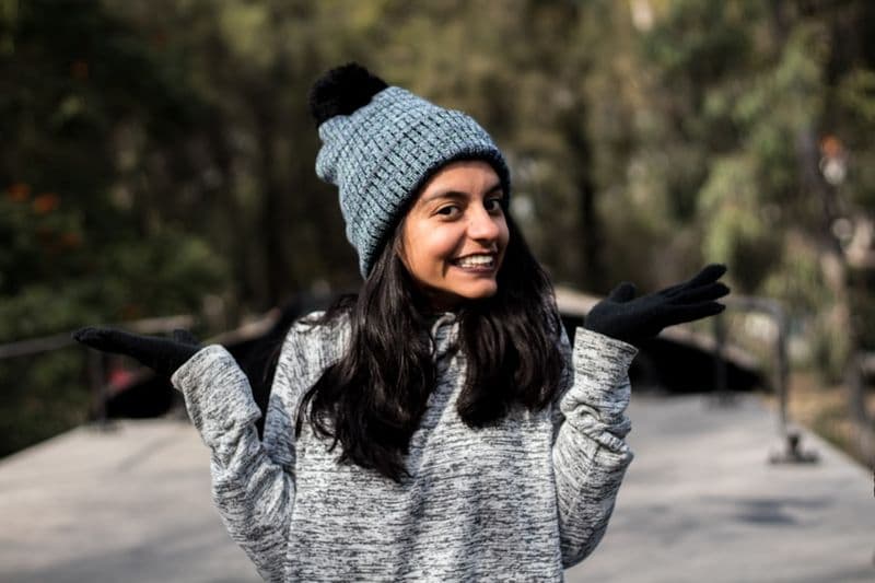 Close view of a grey marled knit sweater and beanie outdoors.